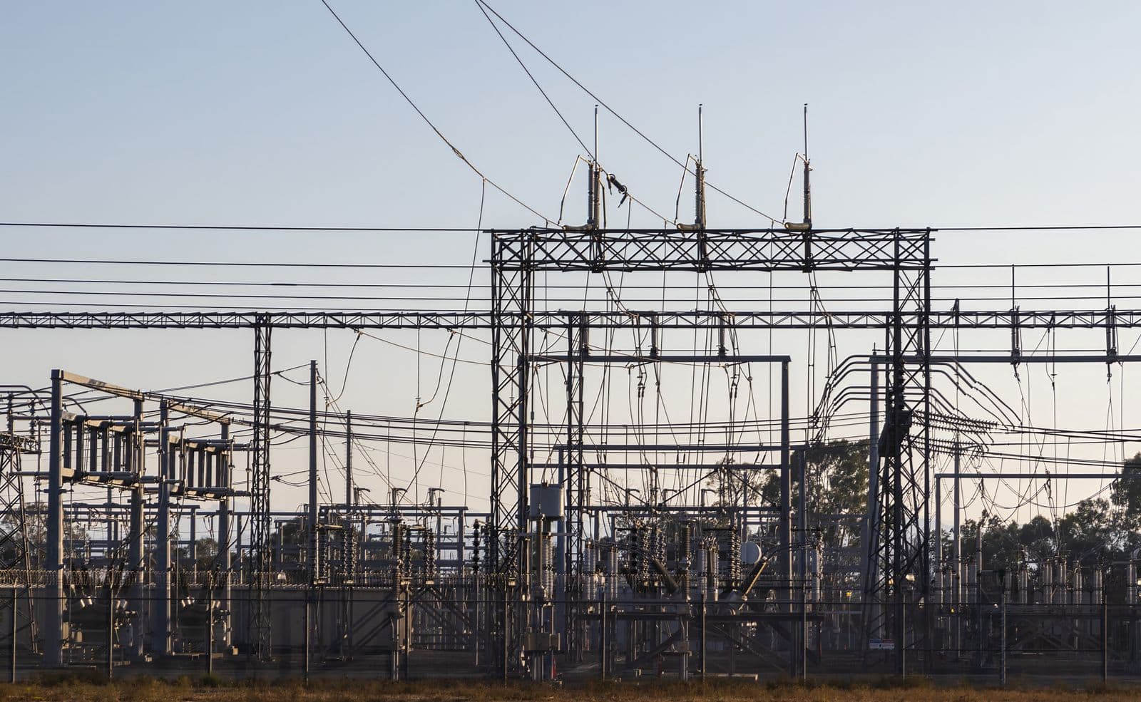 High-voltage electrical substation with steel lattice structures and transmission lines.