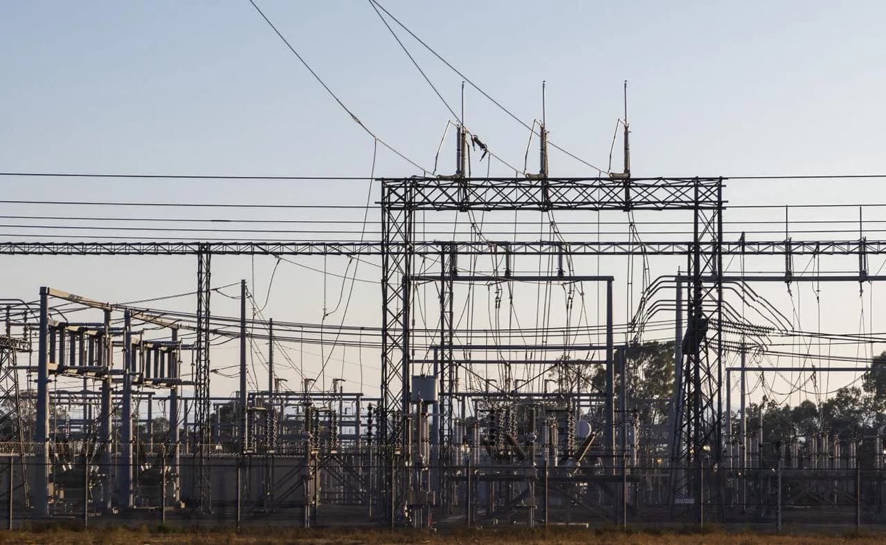 Outdoor electrical substation with steel lattice frames, transformers, and overhead power lines.