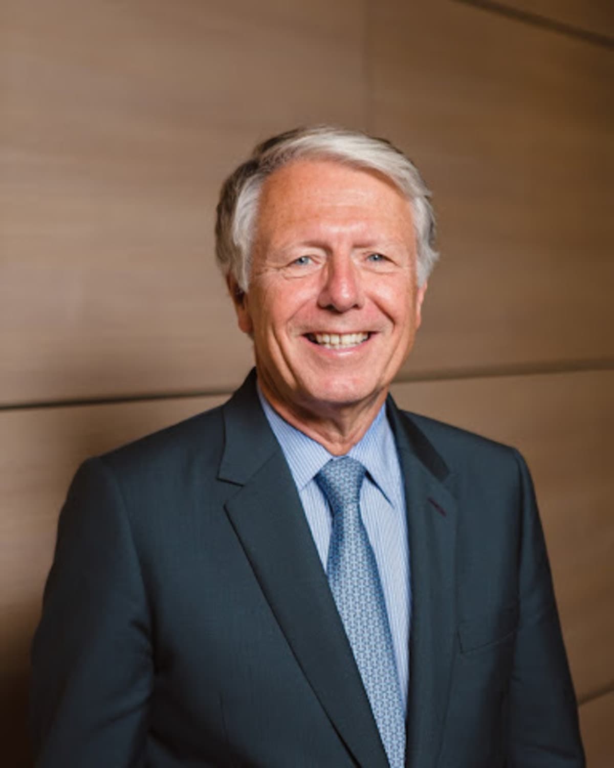 Michel Augonnet smiling in a dark suit and light blue tie.